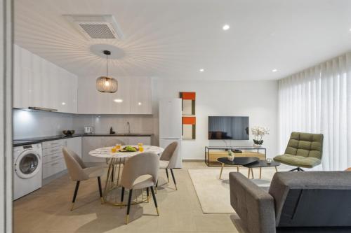 a kitchen and living room with a table and chairs at Sunflower Gem by Homie in Caniço