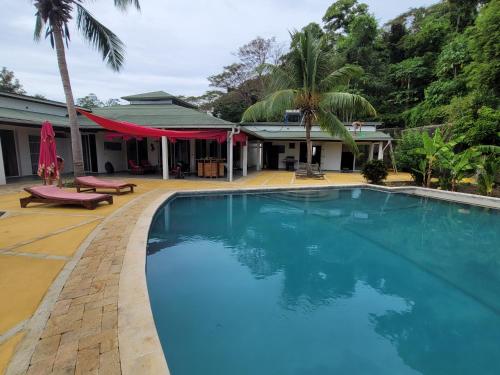 a large blue swimming pool in front of a house at Villa Les Cocotiers in Nosy Be