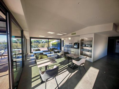 un salon avec des chaises, des tables et des fenêtres dans l'établissement Lamal Hotel Napoli, à Naples