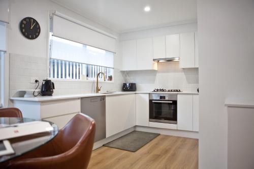 a kitchen with white cabinets and a clock on the wall at Entire home in Cranbourne West in Cranbourne West