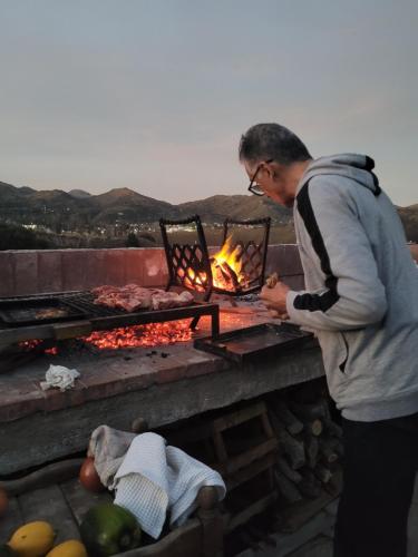 a man cooking meat over an open grill at Punta El Tesoro - Playa Privada al Lago in Potrero de los Funes