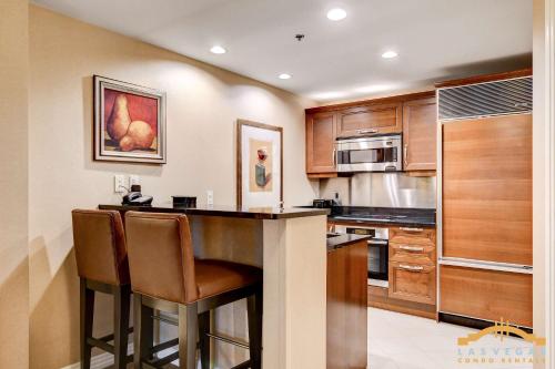 a kitchen with wooden cabinets and a bar with stools at MGM Signature-09-821 1Br2Ba F1 Strip View Balcony Suite in Las Vegas