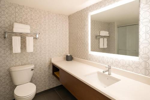 a bathroom with a toilet and a sink and a mirror at Holiday Inn Portland- I-5 S Wilsonville by IHG in Wilsonville
