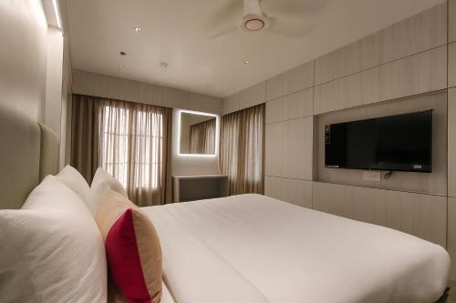 a bedroom with a white bed and a flat screen tv at Aceotel Premier Ujjayanta, Ujjain in Ujjain