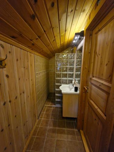 bagno con pareti in legno, lavandino e specchio di Fjellvang a Haglebu