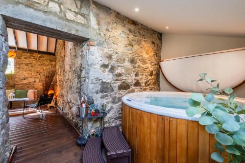 a bathroom with a large tub in a stone wall at Tullymurry House in Ardarragh