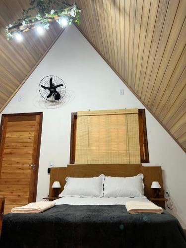 a bedroom with a large bed with a clock on the wall at Chalé Alpes da Nascente in Salesópolis