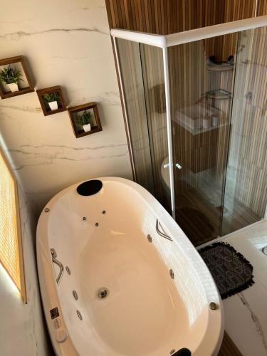 a white bath tub in a bathroom with a shower at Chalé Alpes da Nascente in Salesópolis