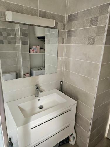 a bathroom with a white sink and a mirror at T2 cosy piscine - proche plages et bourg in Sainte-Anne