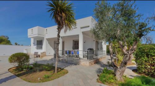 een wit huis met een palmboom ervoor bij Elements Rooms in Porto Cesareo