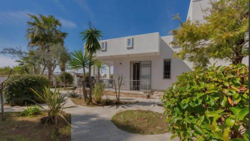 een wit huis met bomen ervoor bij Elements Rooms in Porto Cesareo