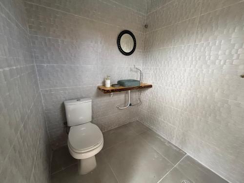 a bathroom with a toilet and a shelf on the wall at Moreno Guest House com Piscina, churrasqueira Praia de Itaguaré e Riviera in Bertioga