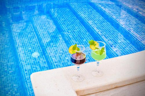 Villa Palace Al Nera في تروغير: كأسين من النبيذ يجلسون بجوار حمام السباحة
