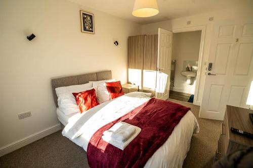 a bedroom with a large bed with red pillows at Modern Ensuite Studio with Free Parking in Stoke on Trent