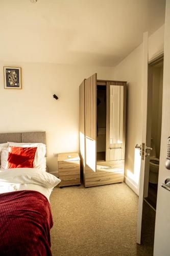 a bedroom with a bed and a dresser and a mirror at Modern Ensuite Studio with Free Parking in Stoke on Trent