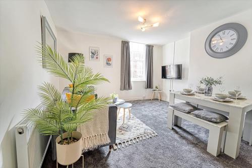 a living room with a clock on the wall and a plant at New Street - City Centre! in Worcester