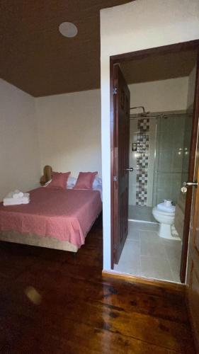 a bedroom with a bed and a bathroom with a toilet at Posada Casa Linda in Pijao