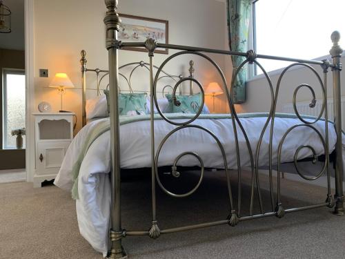 une chambre avec un lit en métal avec des draps blancs dans l'établissement Wardenlea, à Scorton