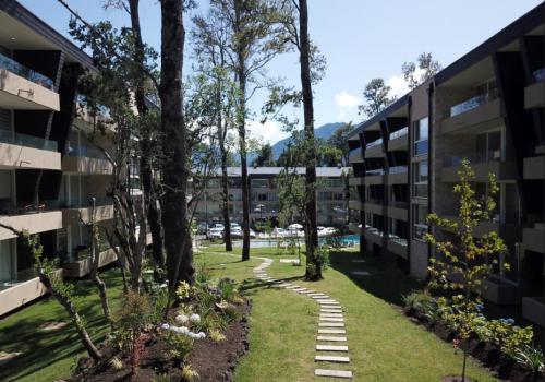 Un patio de un edificio de apartamentos con árboles y césped. en Entorno Natural, cerca del centro de Pucón Parking Privado, en Pucón