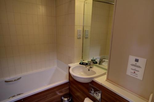 a bathroom with a sink and a bath tub at The Rochford Hotel in Southend-on-Sea