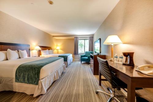 Heritage Hotel, Golf, Spa & Conference Center في Southbury: غرفة فندقية تحتوي على سرير كبير ومكتب وطاولة