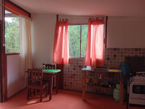 a kitchen with a table and a window with red curtains at El Romance in Jaureguiberry