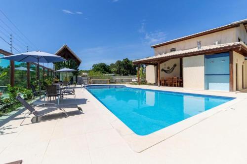 een zwembad met een parasol en een huis bij Refúgio Casa Pitinga in Porto Seguro