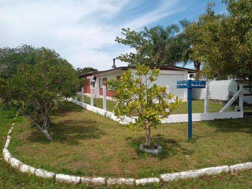 een huis met een bord in een tuin met twee bomen bij Casa de praia ideal para relaxar in Torres
