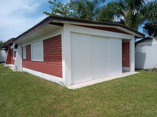 een garage met witte deuren aan de zijkant van een huis bij Casa de praia ideal para relaxar in Torres