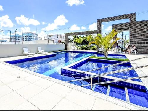 una piscina con piastrelle blu su un edificio di APT 2 QUARTOS c AR, PISCINA E VARANDA Pertinho da Praia de Aruana ad Aracaju