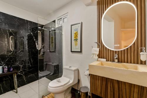 een badkamer met een wastafel, een toilet en een spiegel bij Villa Lol Tun Breakfast and Beach Club Included in Isla Mujeres