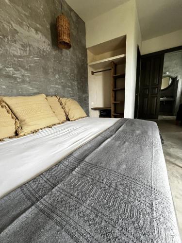 a large bed in a room with a wall at Boutique Hotel EL NIDO Holbox in Holbox Island