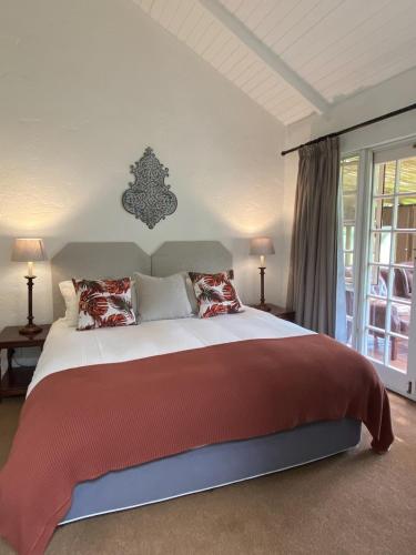 a bedroom with a large bed with red blankets and pillows at Willow Weir River Cottage in Dullstroom