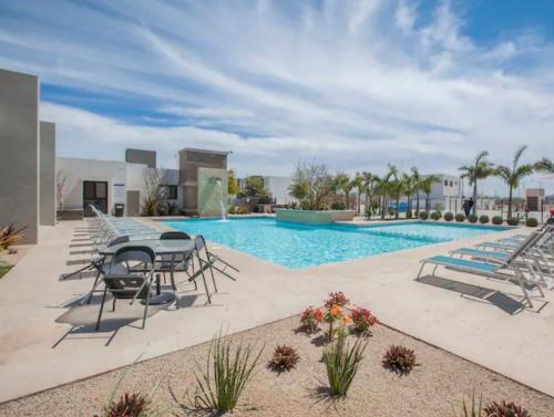 拉巴斯Casa de Las Olas的旁边有桌子和椅子的游泳池