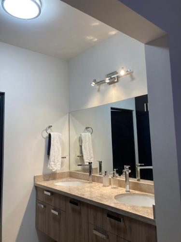 a bathroom with two sinks and a large mirror at Casa de Las Olas in La Paz