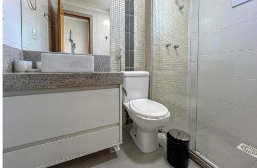 Un baño con inodoro, lavabo y ducha. en Apartamento Centro, en Guarapari