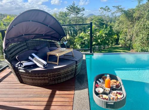 a circular seat with a tray of food next to a swimming pool at The Cassowary - Luxury Rainforest Retreat in Cassowary
