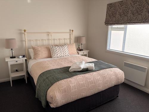 a bedroom with a bed with two tables and a window at Queensly Cottage in Portland