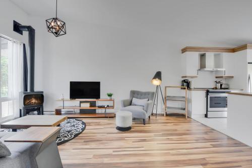 a living room with white walls and wooden floors and a kitchen at Agora Trio Portneuf - 3 Family Units - Spa & Nature in Pont-Rouge