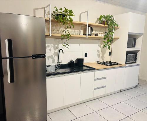 a stainless steel refrigerator in a kitchen with white cabinets at Casa aconchegante pertinho da Praia Central in Itapema