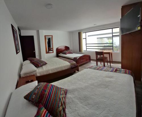 una habitación de hotel con dos camas y una mesa en Hotel San Marcos Las Lajas, en Ipiales