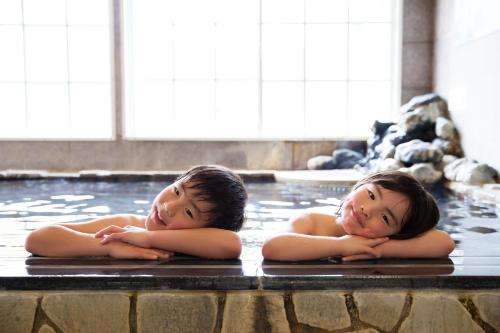 two young children laying in a hot tub at Karuizawa Hotel Paipuno Kemuri in Karuizawa