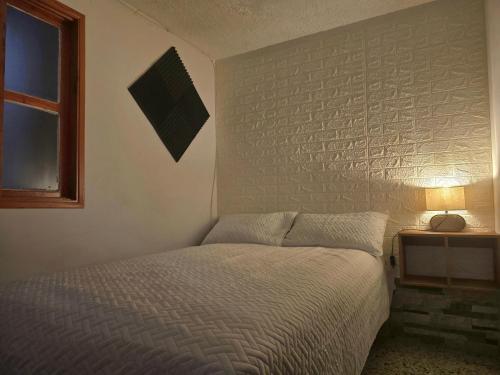 um quarto com uma cama e uma parede de tijolos em Rincon Urbano Tunja Alojamiento em Tunja