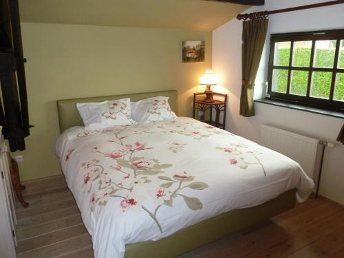 a bed with a white comforter with flowers on it at Five-Bedroom Holiday Home in Somme-Leuze in Somme-Leuze