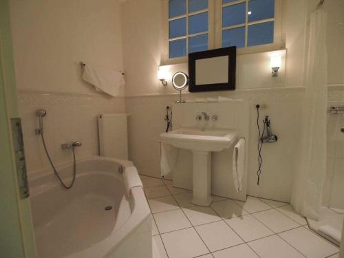 un bagno bianco con lavandino, vasca e lavandino e un lavandino di Holiday apartment with 2 bedrooms a Rattelvitz