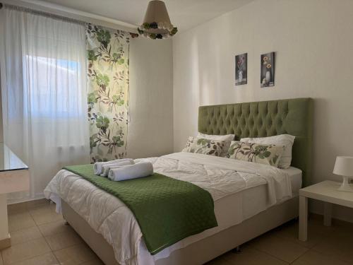 ein Schlafzimmer mit einem großen Bett mit grünem Kopfteil in der Unterkunft Orange House in Keramotí