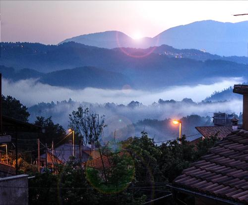 a view of a foggy valley with the sun rising behind mountains at Casa Vacanze Antico Poggio in Poggio San Giovanni