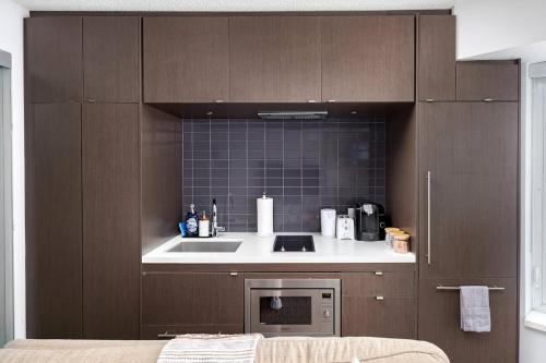 a kitchen with a sink and a microwave at Plush Yorkville Designer Condo with Glam Suite in Toronto