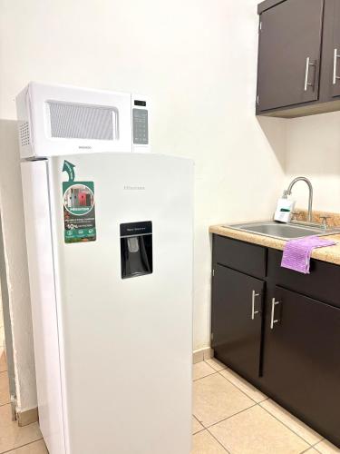 a white refrigerator with a microwave on top of it at Cómodo departamento 2 cerca del centro de gobierno , CAS, Consulado , CRIT in Hermosillo