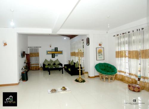 a living room with a green couch and a cross on the wall at Tea Escape Holiday Villa and Cabanas in Gampola
